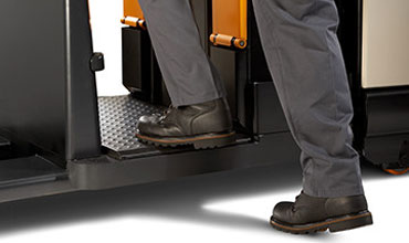 Operator stepping onto the PC series rider pallet truck with operator-sensing floorboard